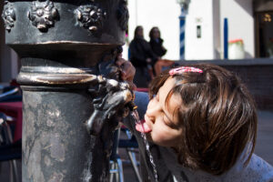 Bambina che beve alla fontana